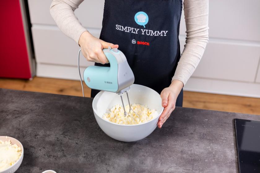 Frischkäse-Frosting wird mit einem Handmixer verrührt.