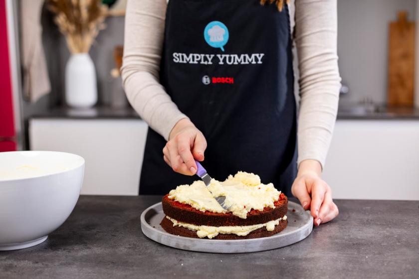 Red Velvet Cake wird mit Frosting eingestrichen.