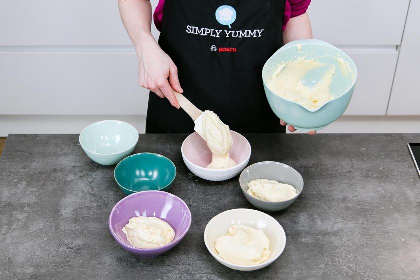 Der Teig für den Regenbogenkuchen wird auf sechs kleine Schüsseln verteilt.