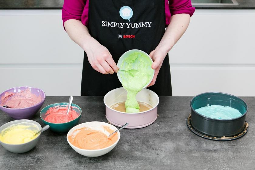 Grüner Teig für den Regenbogenkuchen wird in eine Springform gegeben.