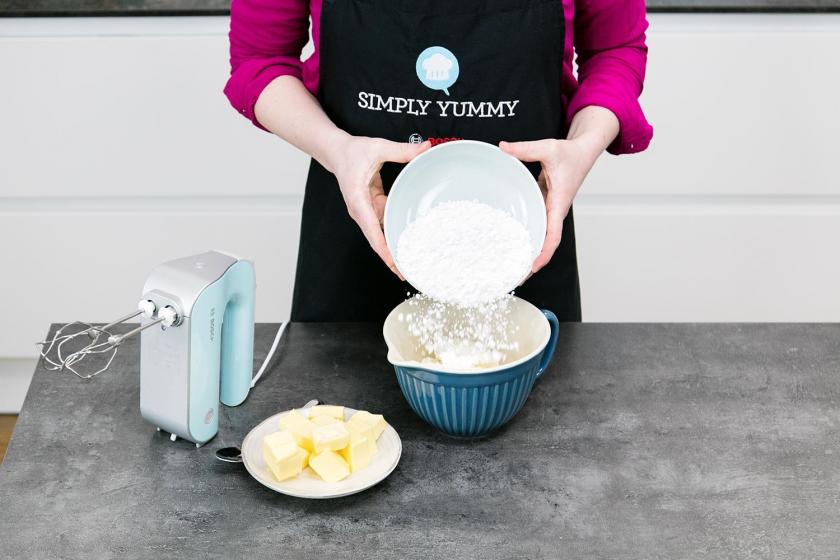 Für das Frosting für den Regenbogenkuchen wird Puderzucker in eine Rührschüssel gegeben.