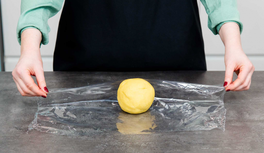 Der Teig für den Rhabarberkuchen mit Quark wird in Folie eingeschlagen.