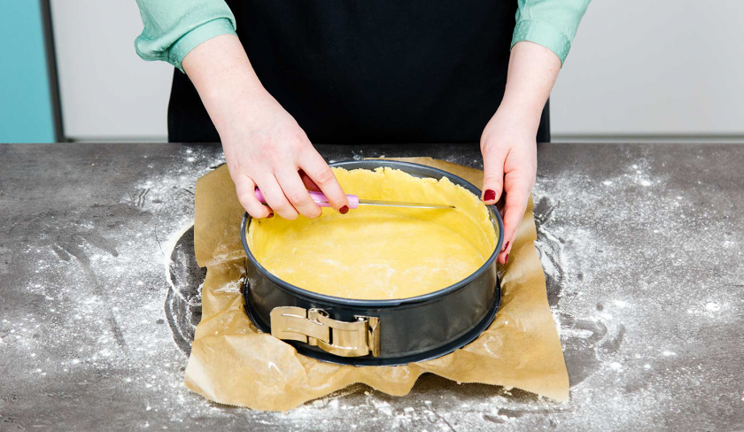 Der Teig für den Rhabarberkuchen mit Quark wird in die Backform gelegt und ein Rand hochgezogen.