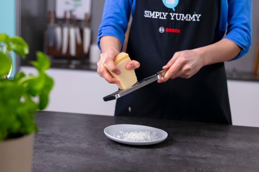 Parmesan wird mit einer Kuchenreibe gerieben.
