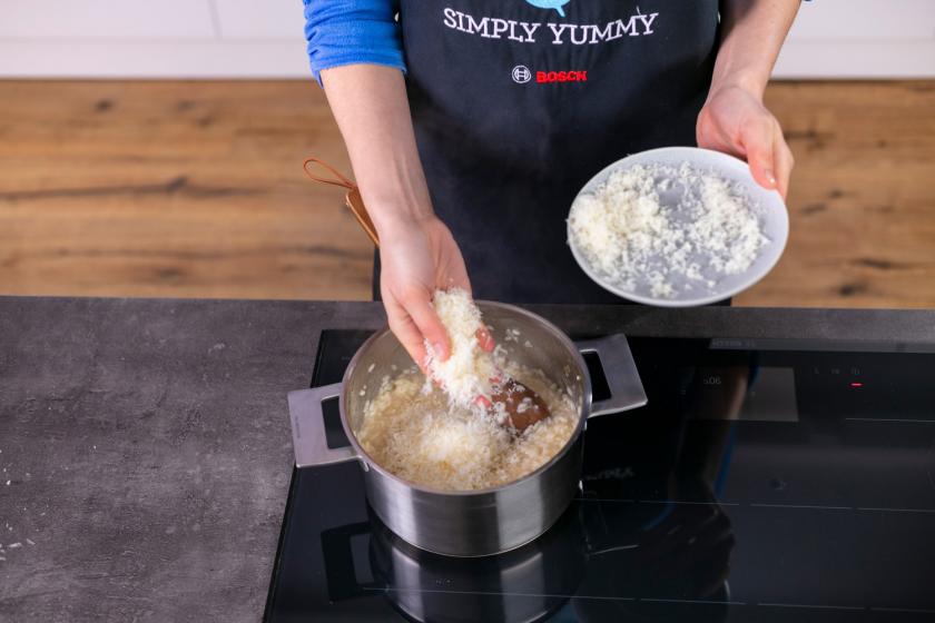Parmesan wird unter das Risotto gegeben.