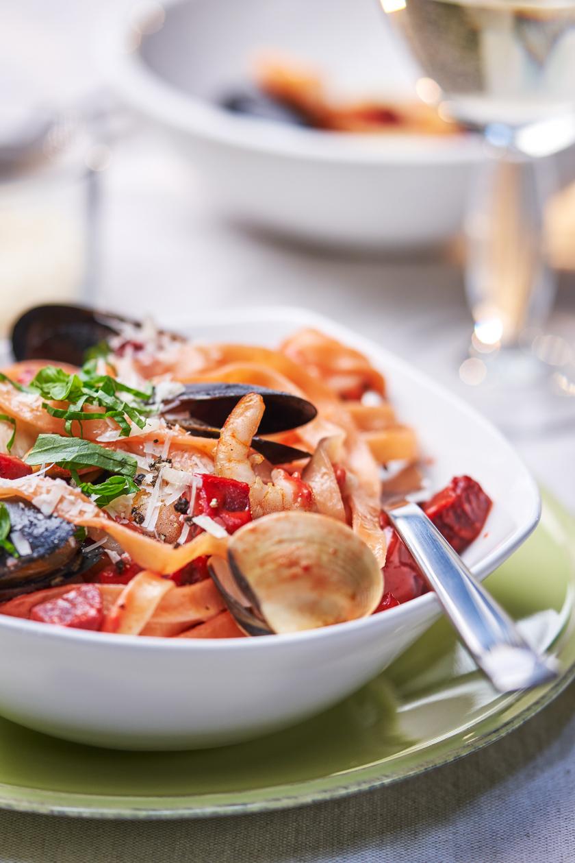 Rote Bete Tagliatelle mit Meeresfrüchten auf einem Teller angerichtet.