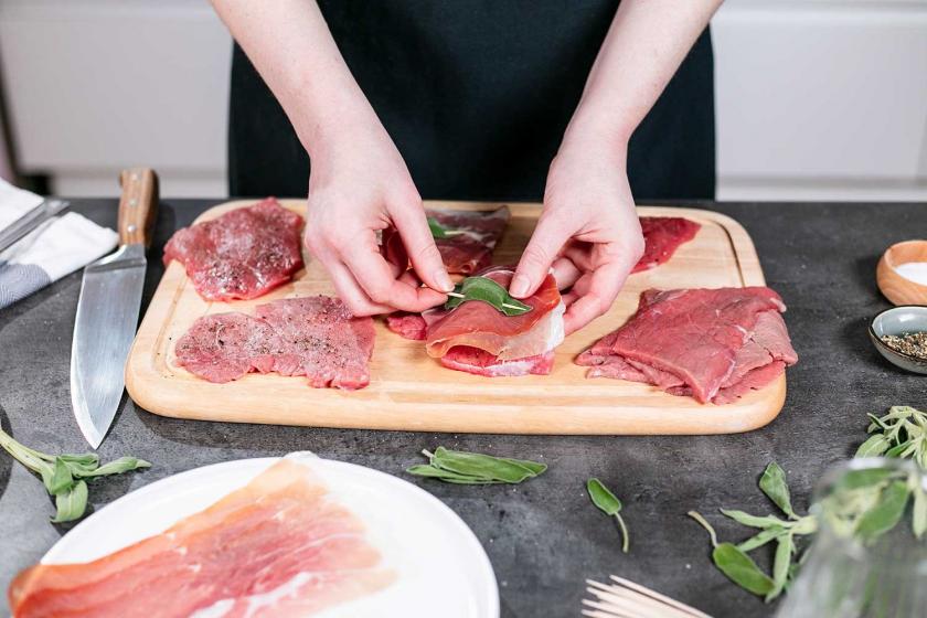 Schinken und Salbei werden mit einem Zahnstocher am Fleisch fixiert.