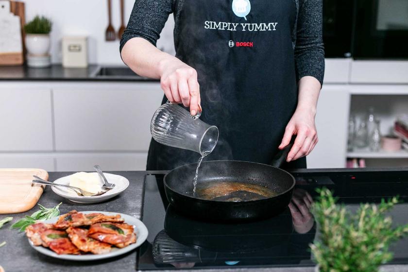 Weißwein wird in die Pfanne gegeben, in der Saltimbocca alla romana gebraten wurden.