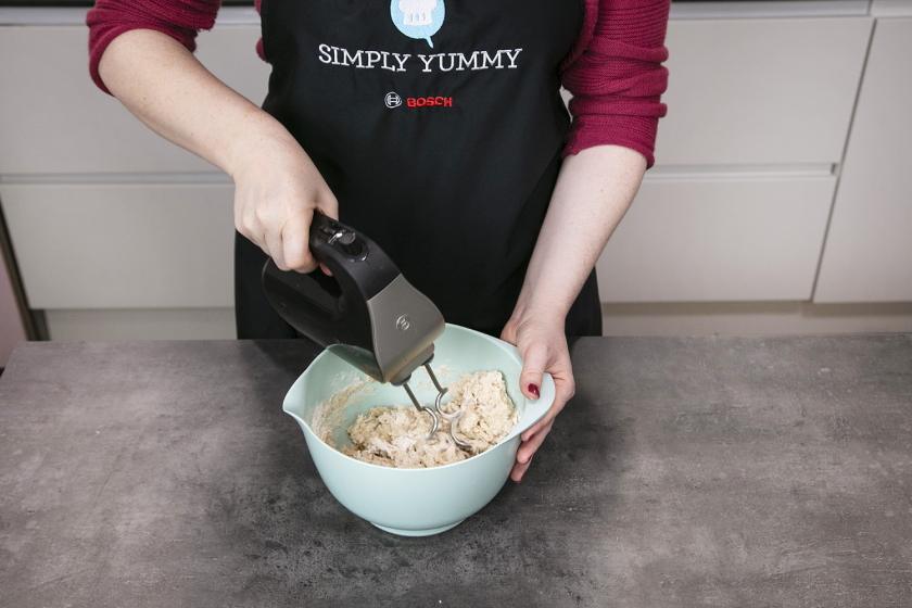 Die Ztaten für das Sauerteigbrot werden in einer Schüssel mit einem Handrührgeräät verknetet.