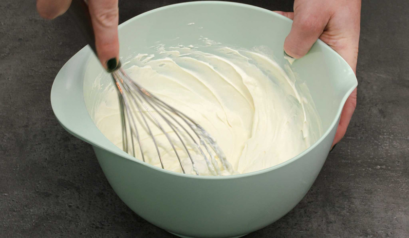 Für die Schmandschnitten mit Glühweinkirschen wird die Schmandcreme mit einem Schneebesen verrührt.