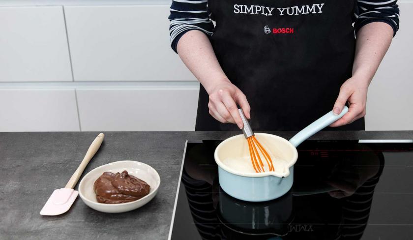 Für die Ganache der Schoko-Bananen-Torte wird Sahne in einem Topf erhitzt.