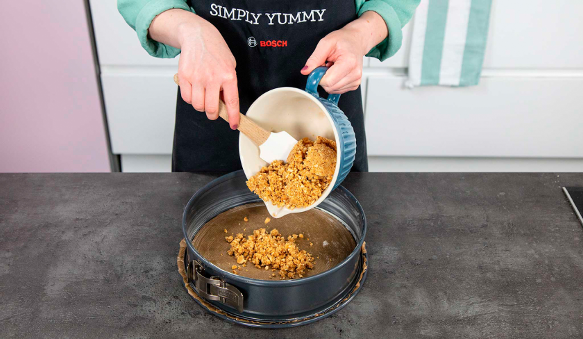 Die Keksmasse für den Boden de Schoko-Käsekuchens wird auf die Springform gegeben.