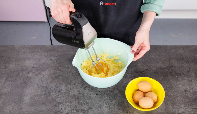 Die Zutaten für die Füllung des Schoko-Käsekuchens werden in einer Schüssel mit einem Handrührgerät verrührt.