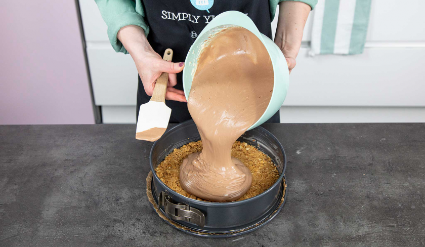 Die Füllung vom Schoko-Käsekuchen wird auf den Keksboden gegeben.