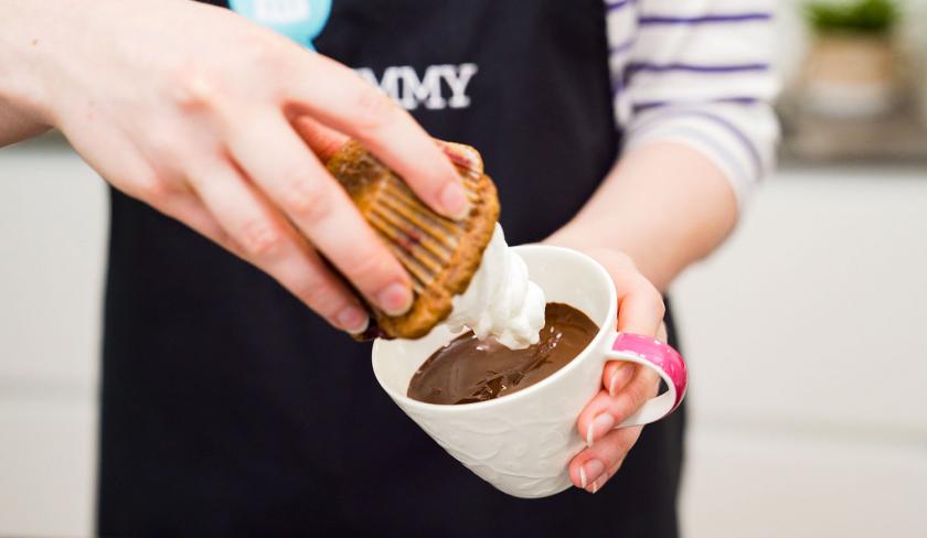 Ein Schoko-Kirsch-Muffins wird kopfüber in flüssige Schokolade getaucht.