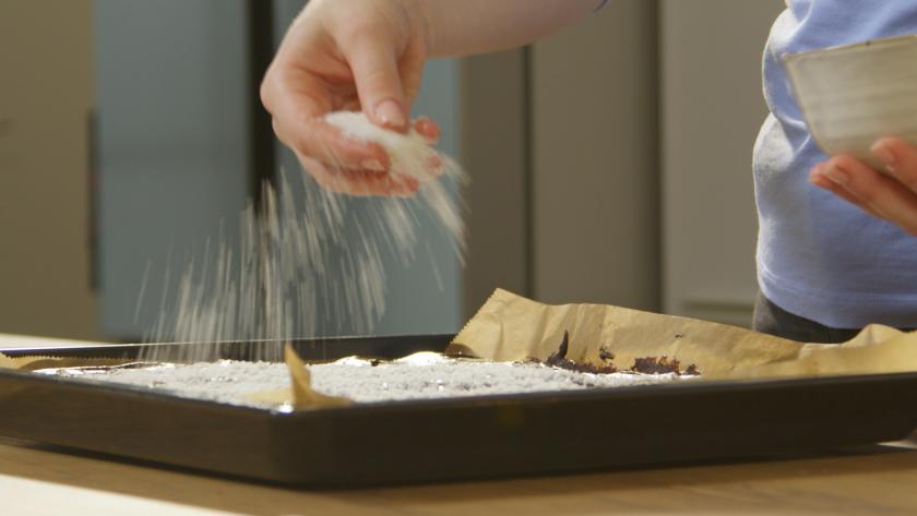 Kokosflocken werden über die Schoko-Kokos-Schnitten gestreut.