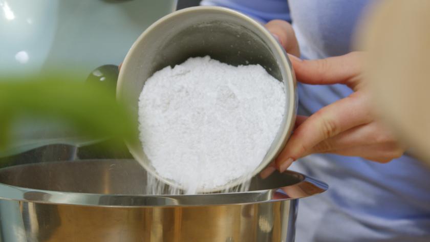 Puderzucker wird in die Rührschüssel einer Küchenmaschine gegeben.