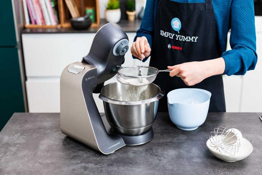 Mehl wird auf die Eimasse für den Schüttelkuchen gesiebt.