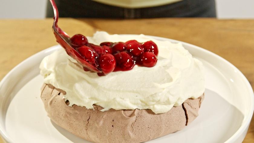 Schwarzwälder Kirsch Pavlova wird mit Kirschen bedeckt.