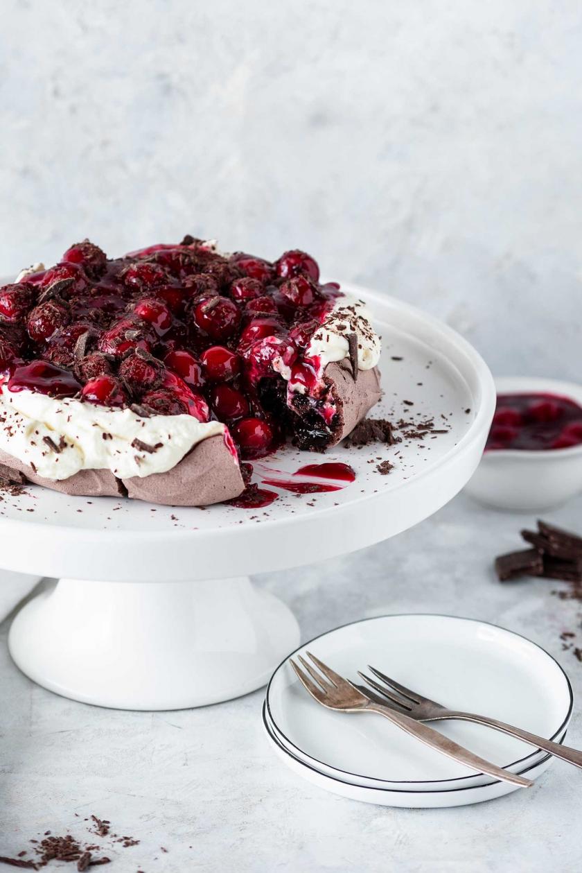 Schwarzwälder Kirsch Pavlova angeschnitten auf einer Tortenplatte.