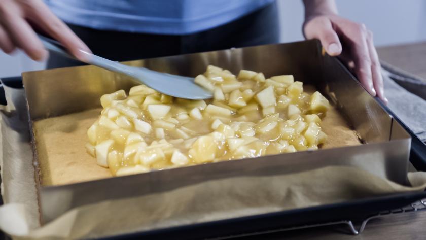 Die Apfelmasse wird auf den Boden des Spekulatius-Apfelkuchens gestrichen.