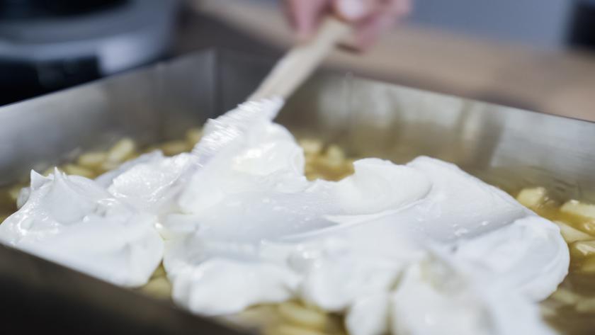 Die Quarkcreme wird auf den Spekulatius-Apfelkuchen verstrichen.