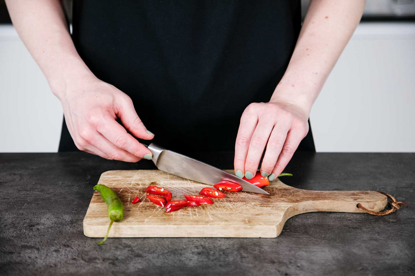 Für zusätzliche Schärfe im Thai Curry werden Chilis geschnitten.