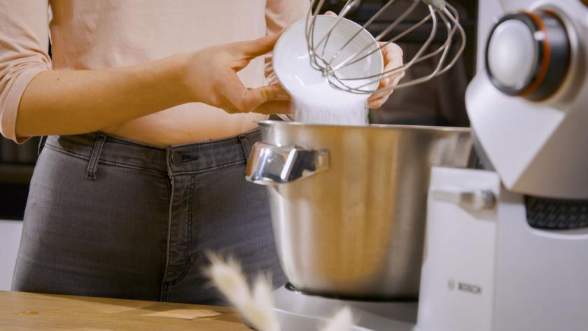Zucker wird in die Rührschüssel einer Küchenmaschine gegeben.