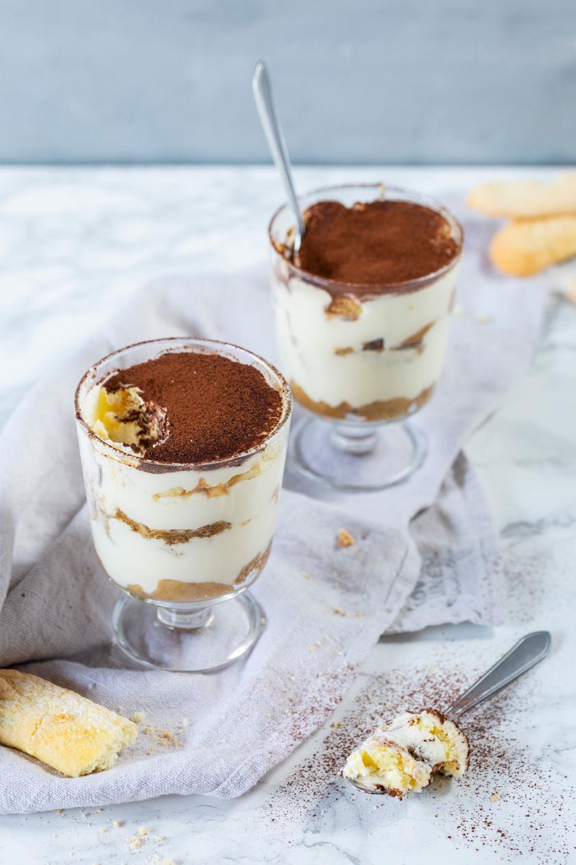 Zwei Tiramisu im Glas auf einem Tisch mit Löffel.
