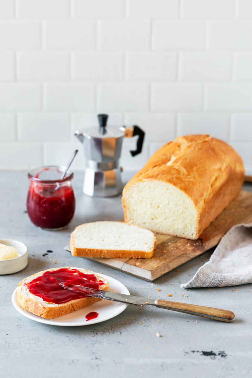 Toastbrot angeschnitten auf einem Brettchen, daneben Butter und Marmelade