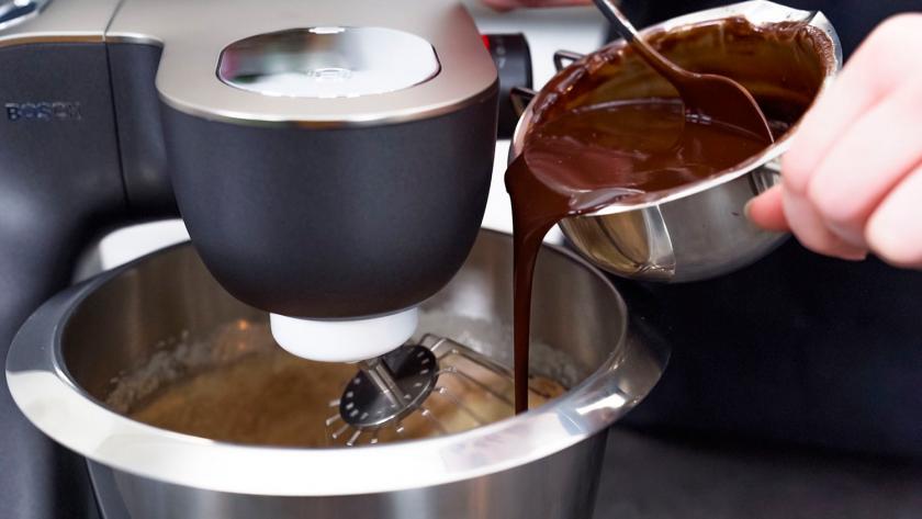 Zum Teig für die Toffifee-Torte wird flüssige Schokolade in die Rührschüssel gegeben.