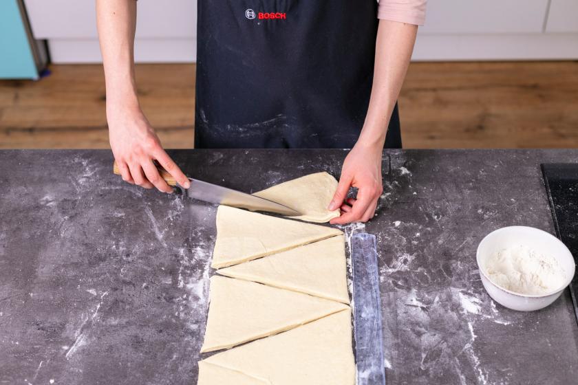 Plunderteig wird für vegane Croissants in Dreiecke geschnitten.