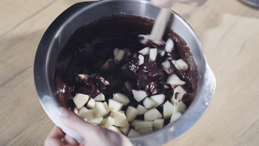 Birnenwürfel werden unter den Teig für den veganen Birnenkuchen gerührt.