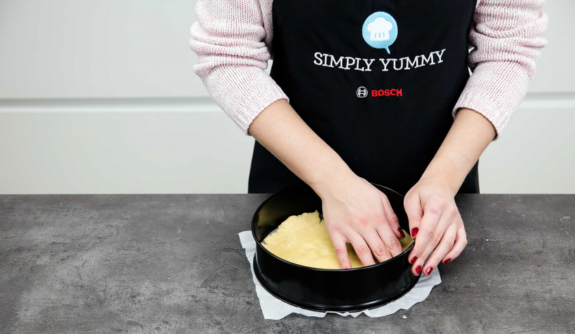 Der Teig für den veganen Käsekuchen wird in eine Springform gedrückt.