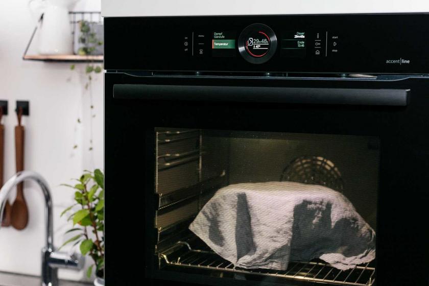 Der Teig für die Vollkornbrötchen steht abgedeckt in einem Backofen.