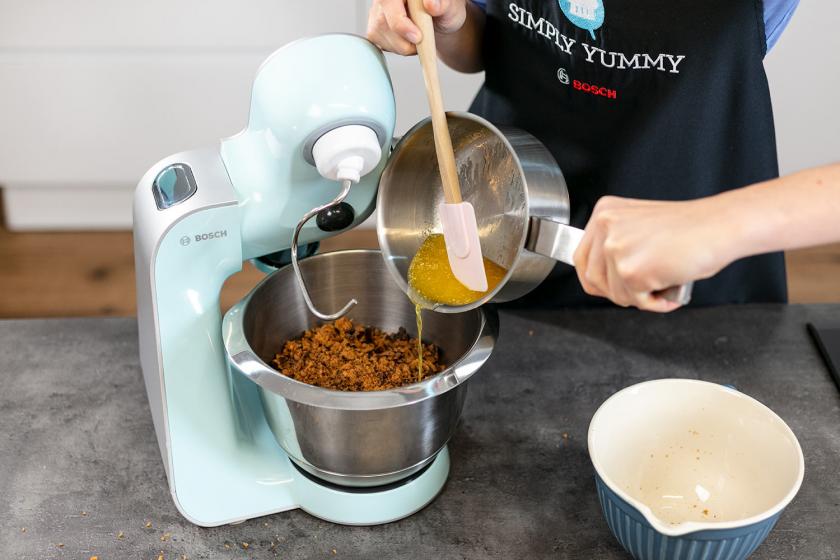 Flüssige Butter wird zu Lebkuchenbrösel in eine Rührschüssel gegeben.