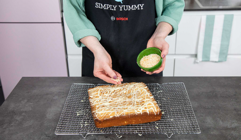 Weiße Schoko-Kokos-Blondies werden mit Schokolade und Kokosraspeln verziert.