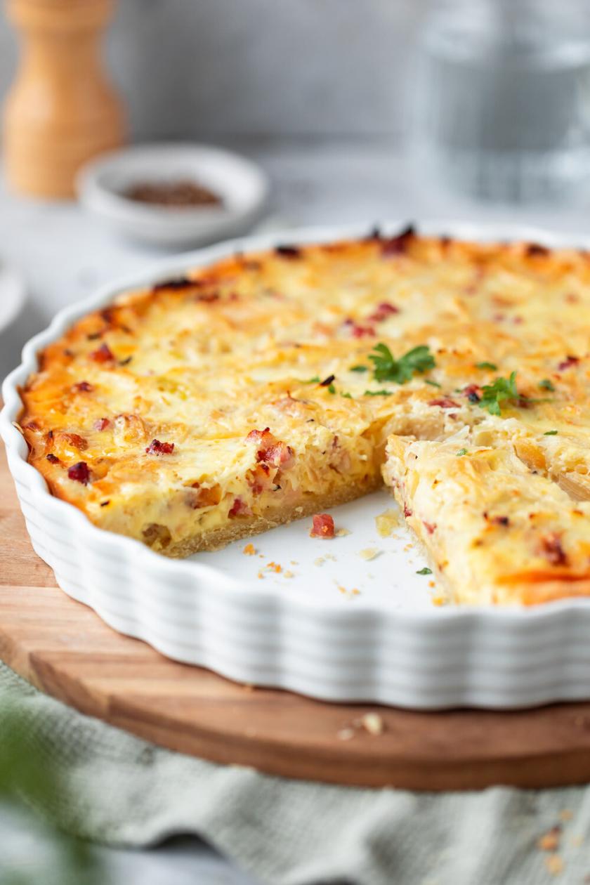 Weißkohl-Quiche mit Speck und Schmand angeschnitten in einer Tarteform auf einem Tisch