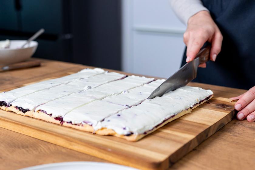 Biskuitplatte für Wickeltorte wird in Streifen geschnitten.