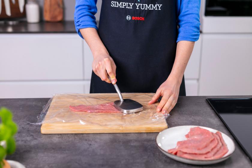 Wiener Schnitzel zwischen Folie wird plattiert.