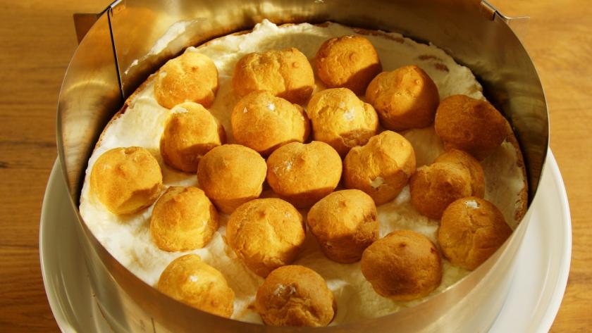 Windbeutel liegen auf dem Boden der Windbeuteltorte mit Himbeeren.