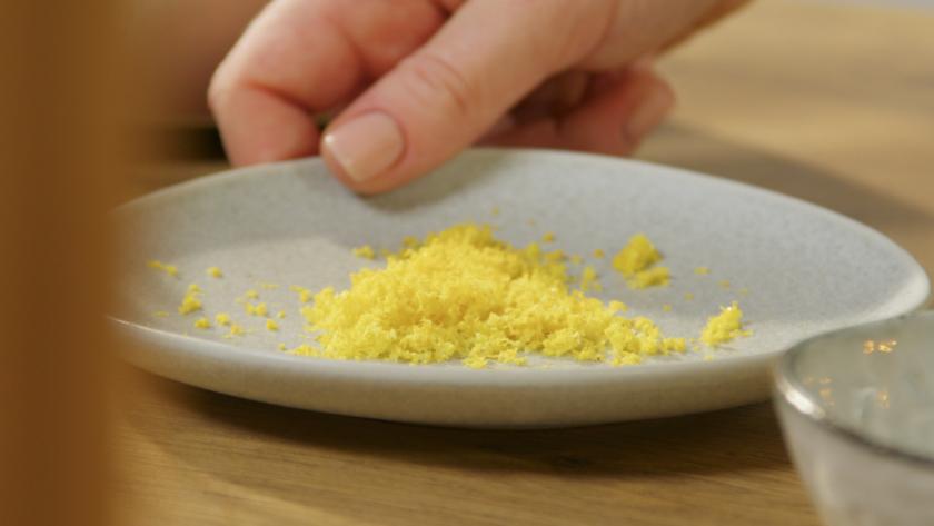 Zitronenschale liegt auf einem Teller.