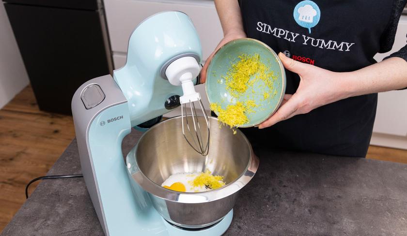 Für den Teig der Zitronen-Blaubeermuffins mit Streuseln wird Zitronenschale in die Rührschüssel einer Küchenmaschine gegeben.