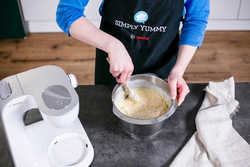 Der teig für den Zitronenkuchen mit Frischkäse wird in einer Schüssel verrührt.