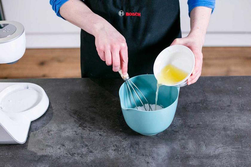 Zitronensaft wird zu Puderzucker in eine Schale gegeben.