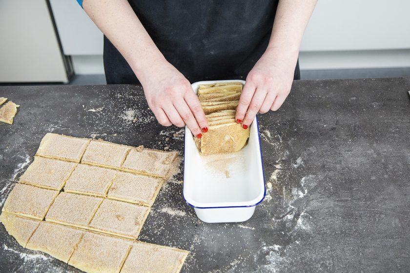 Der Teig für das Zupfbrot wird in eine Kastenform aufrecht geschichtet.