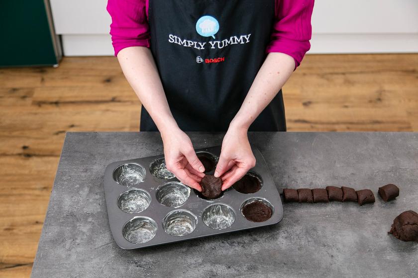 Mürbeteig wird in eine Muffinform gegeben.