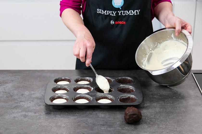 Die Füllung für die Zupfkuchen Muffins wird auf den Teig gegeben.