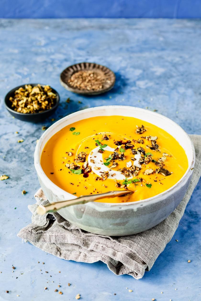 Kürbissuppe mit Toppings und Löffel in einer Schüssel.