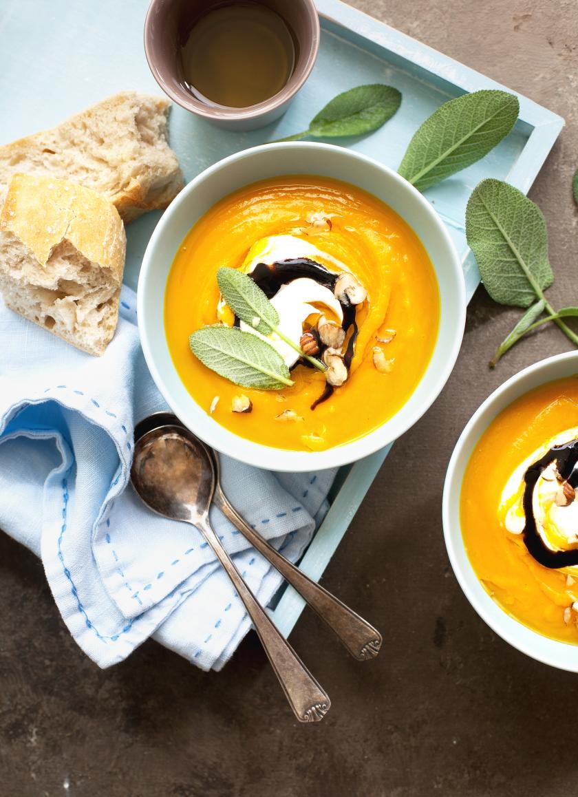 Zwei Schalen Kürbissuppe mit Toppings und angelegtem Löffel.